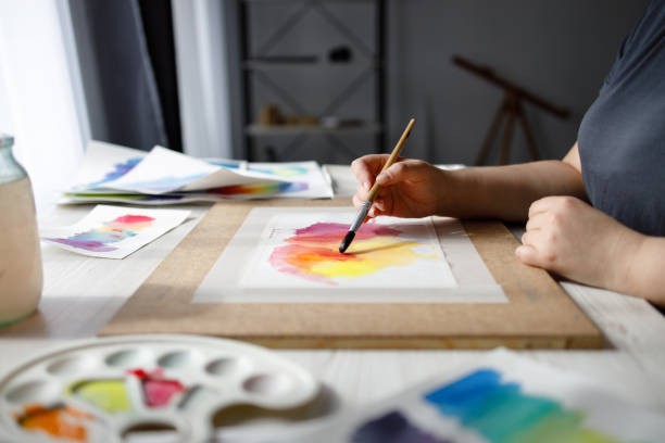 Watercolour paints, brushes and a palette on a table