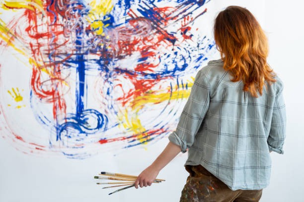 A woman painting an expressive mural in red, blue and yellow