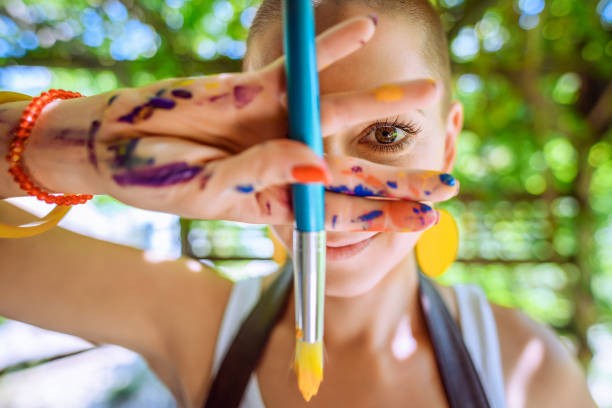 A woman with paint-covered hands holding a brush